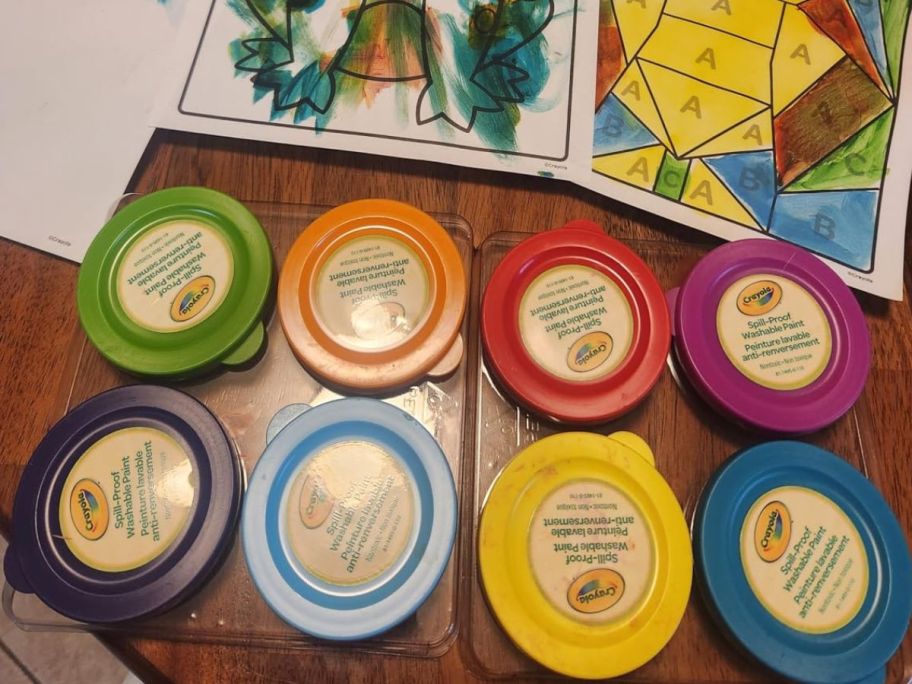 Crayola paints on the table with art work on top