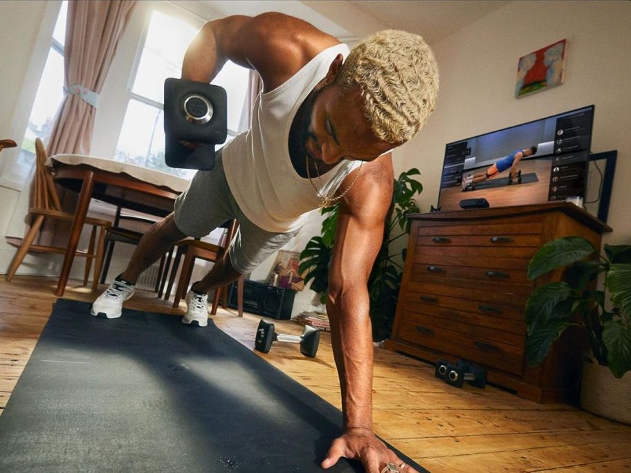 Person working out with a Peloton Guide AI-Powered Personal Strength Training Device For Your TV, one of the college discounts for 2024