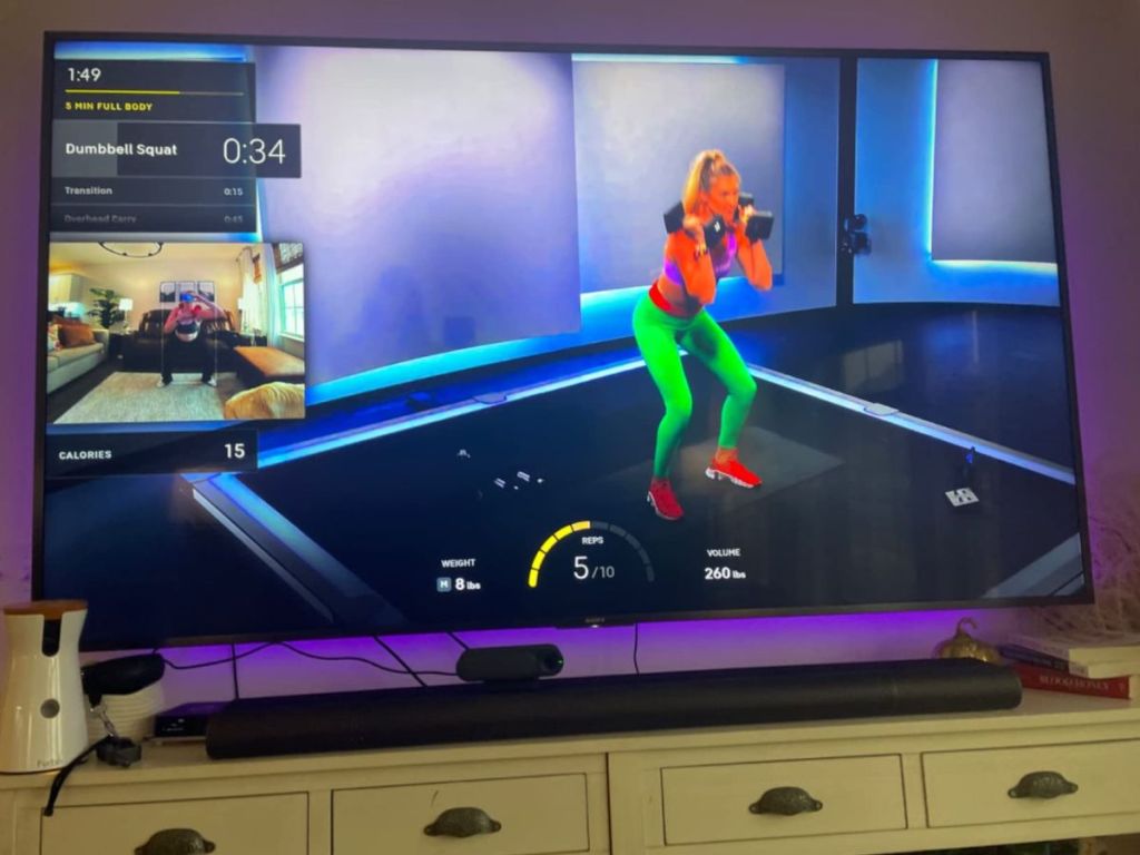 TV showing a person working out and using the Peloton Guide AI-Powered Personal Strength Training Device For Your TV