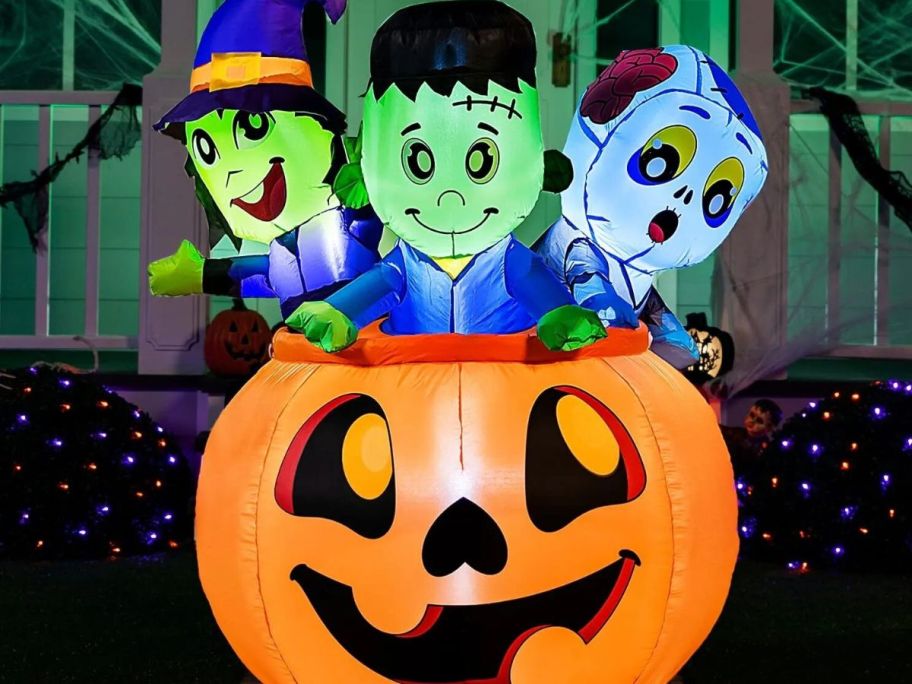 lighted pumpkin inflatable with monsters inside displayed in front of a home