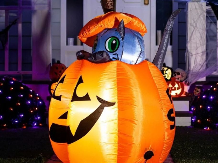 Lighted cat inflatable hald tucked in shown in front of a house 