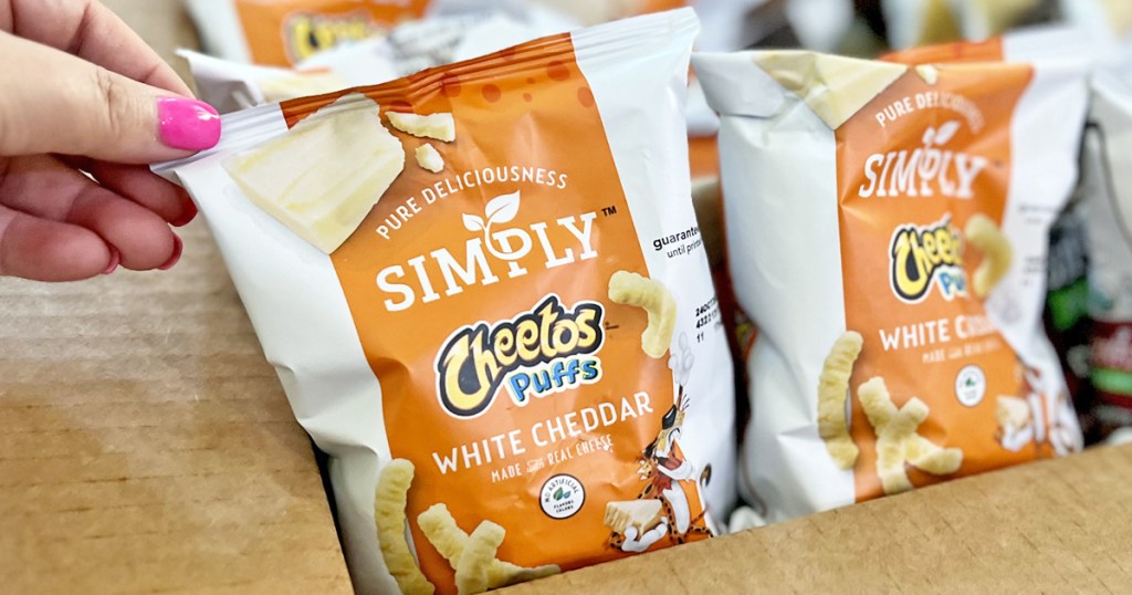 hand grabbing bag of Simply Cheetos from cardboard box