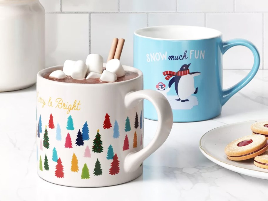 tree and penguin print christmas mugs on kitchen counter