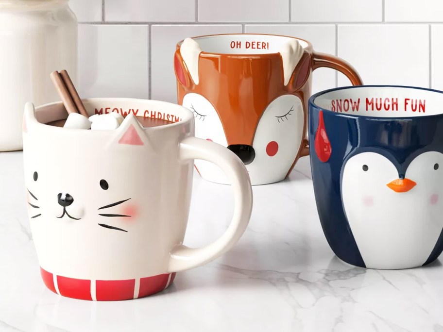 cat, penguin, and deer christmas mugs on kitchen counter