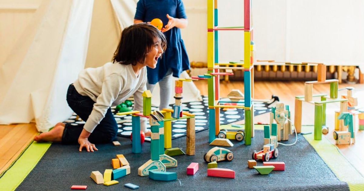 two kids playing with Tegu buliding blocksin a playroom