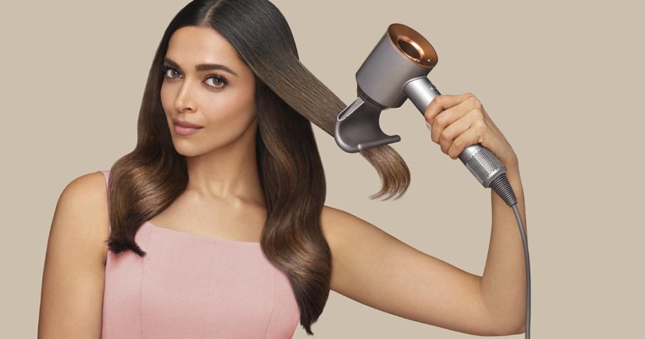 woman using silver and copper hair dryer on her hair