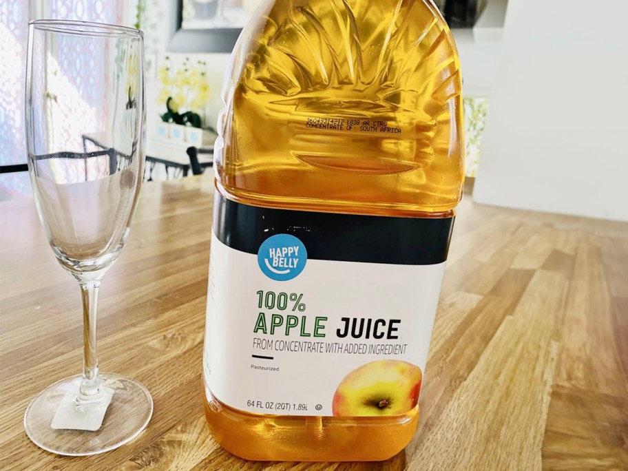 happy belly apple juice bottle on table next to wine glass 