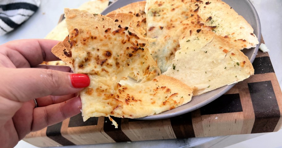 holding a slice of woman cooking tortilla garlic bread in the air fryer