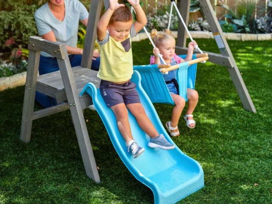 boy sliding down slide on KidKraft My First Wooden Swing Set