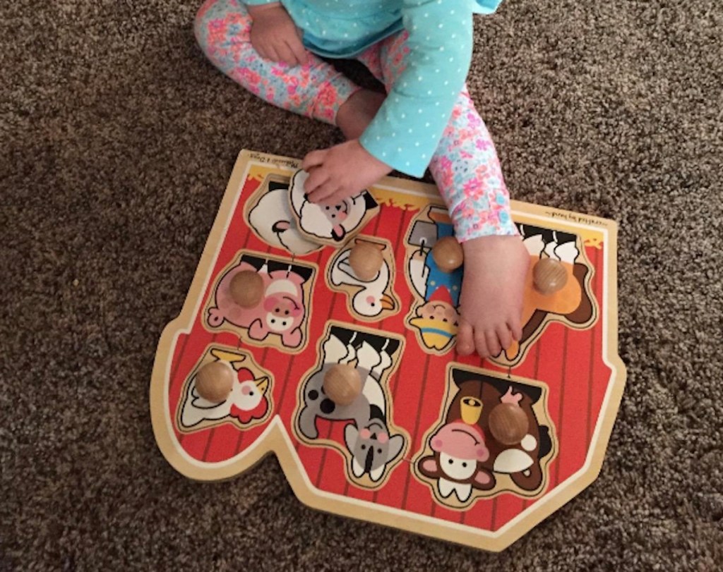 toddler sitting on floor doing wooden farm puzzle