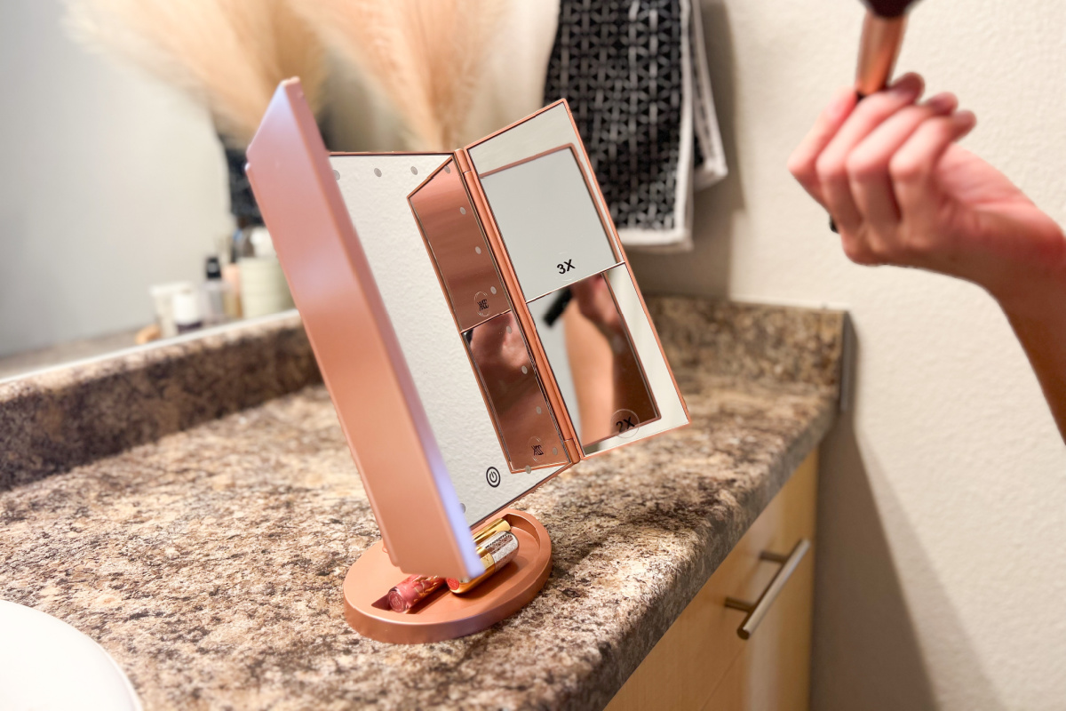 open lighted vanity mirror on the edge of a marble bathroom countertop