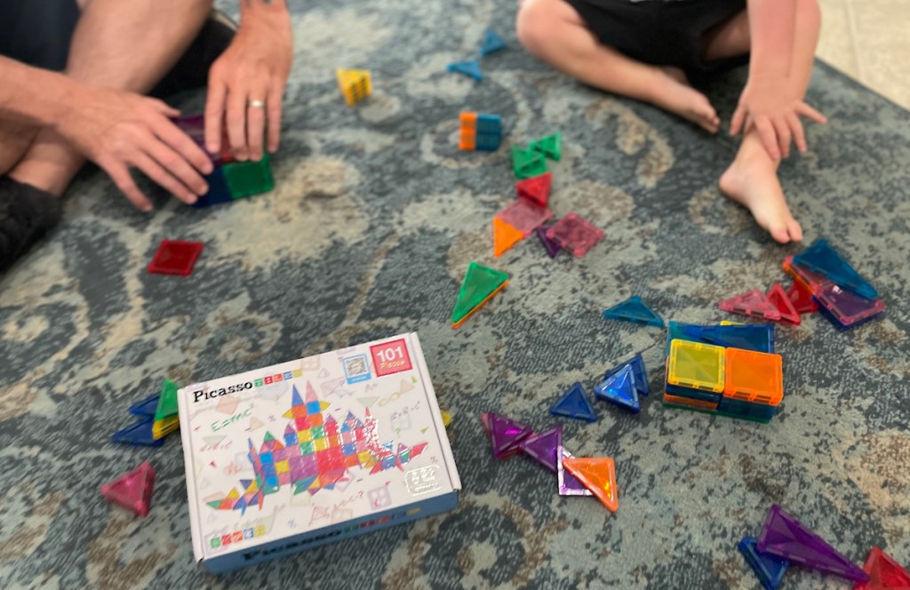 Picasso tiles and box on floor with toddler and man