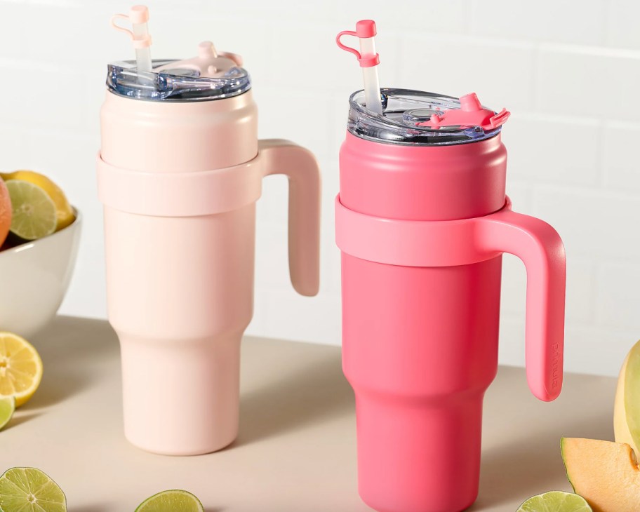 pink and coral straw tumblers next to lemons