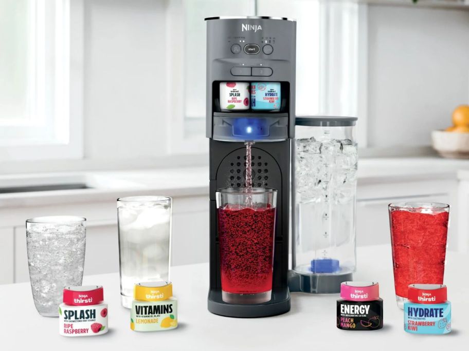 Ninja Thirsti Carbonated Drink System, glasses, and drink mixes on a kitchen counter