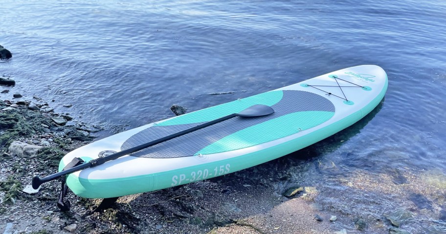 blue and white inflatable paddle board on beach near water
