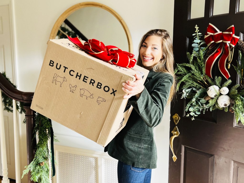 woman carrying a butcher box in door with bow on top of it