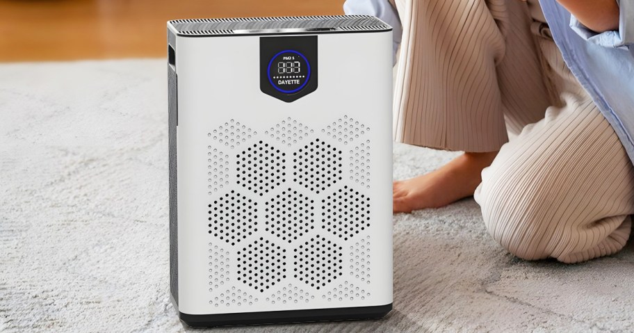 woman kneeling down behind a white air purifier on floor