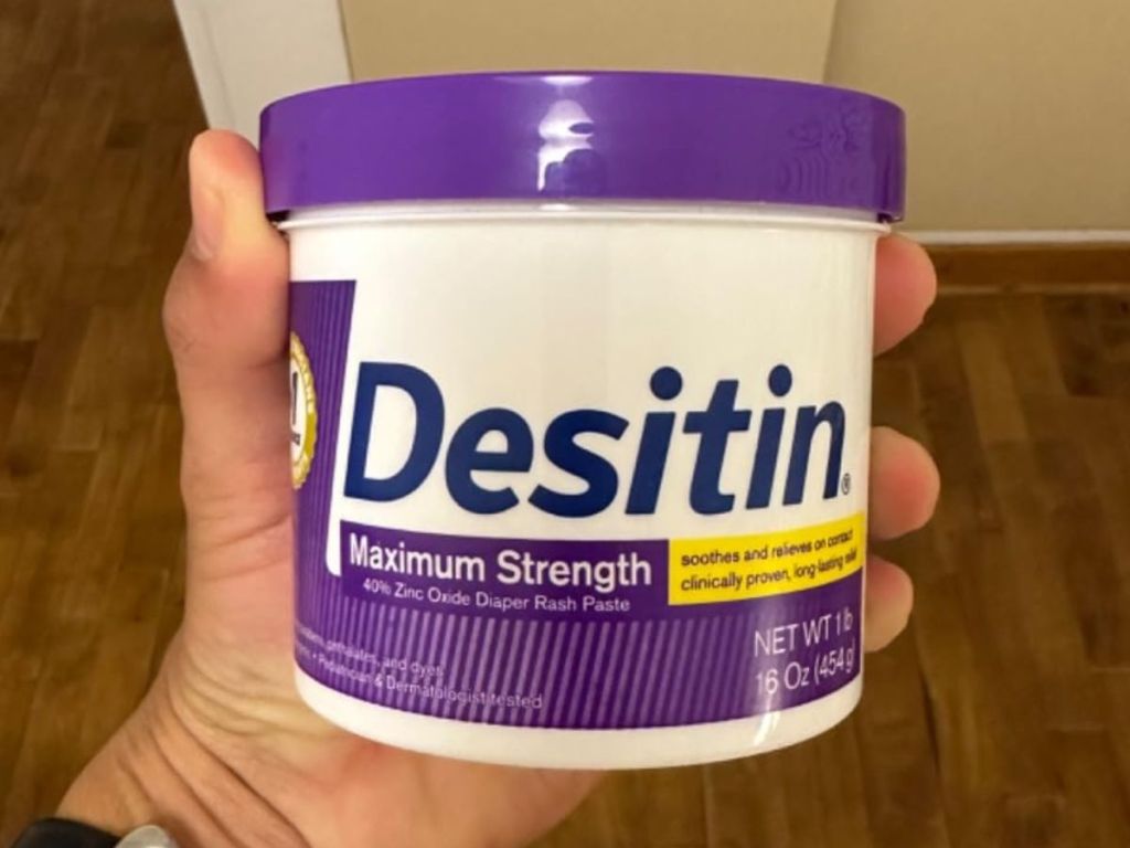 Hand holding a tub of Desitin Max Strength