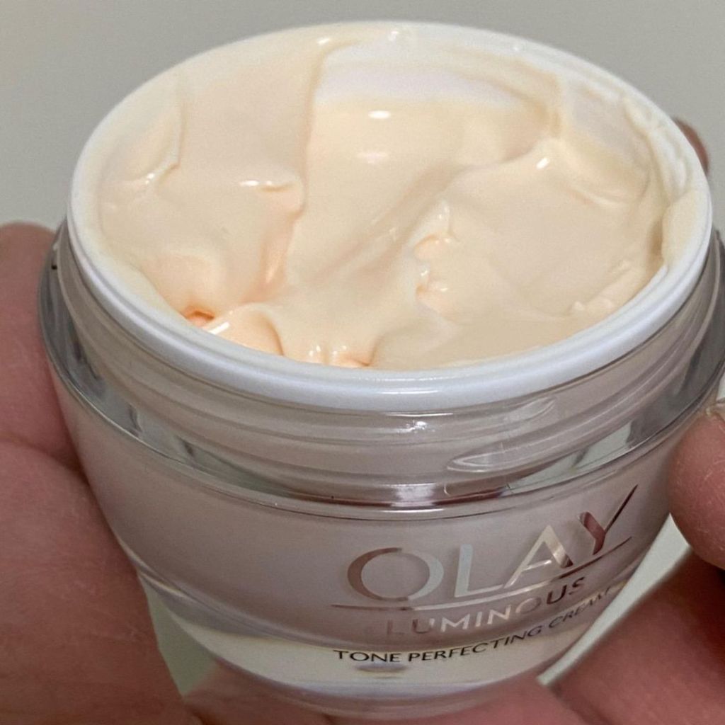 hand holding an open jar of Olay Luminous Tone Perfecting Moisturizer