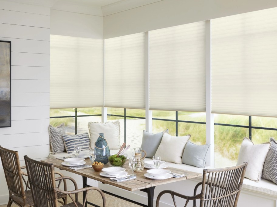 a kitchen breakfast nook / dining table area with large windows and custom blinds