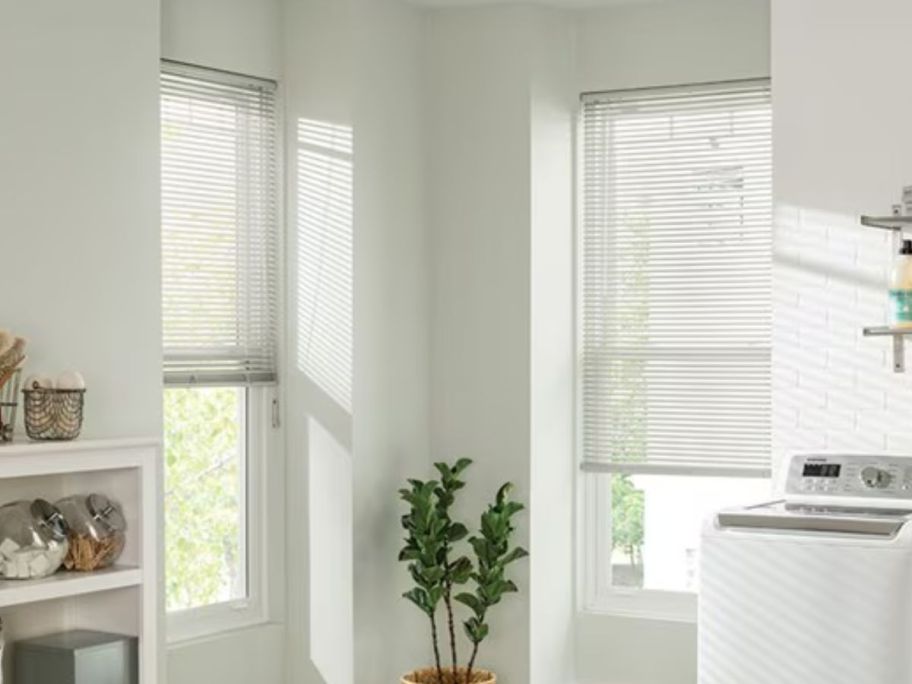 a laundry room with corner windows with white vinyl blinds