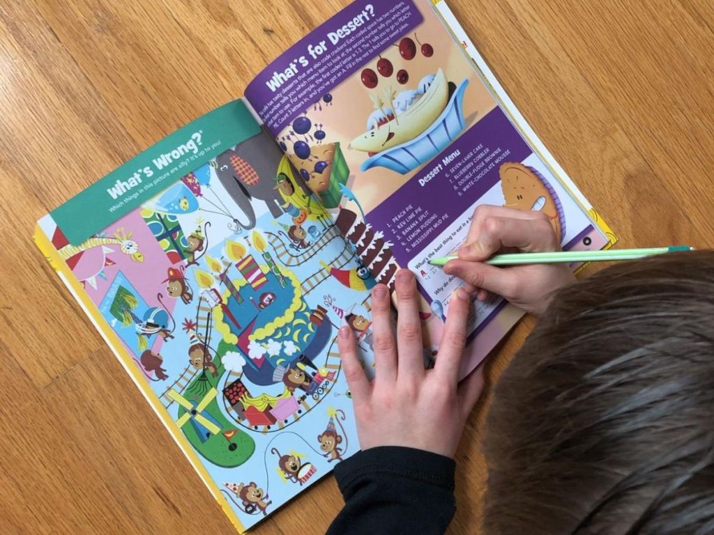 Child writing in a highlights book while laying on the floor