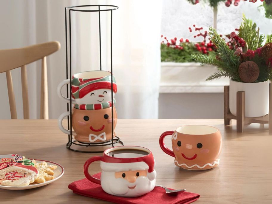 Holiday Time 12oz Holiday Characters Glazed Stoneware Ceramic Stacking Mug Set w/ Metal Rack on table