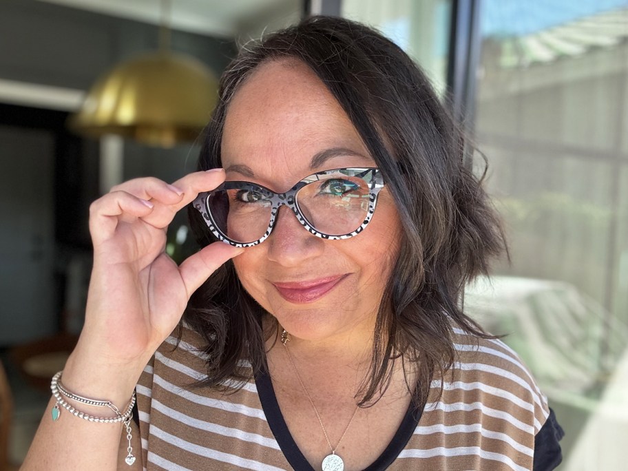 woman in striped shirt touching pair of cheetah print glasses on her face