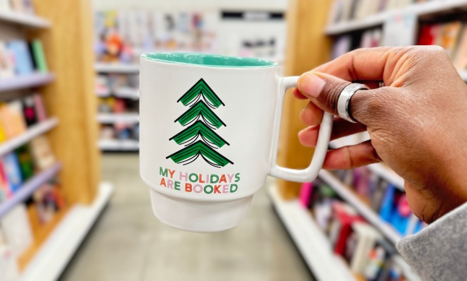 hand holding my holidays are booked mug in store book section