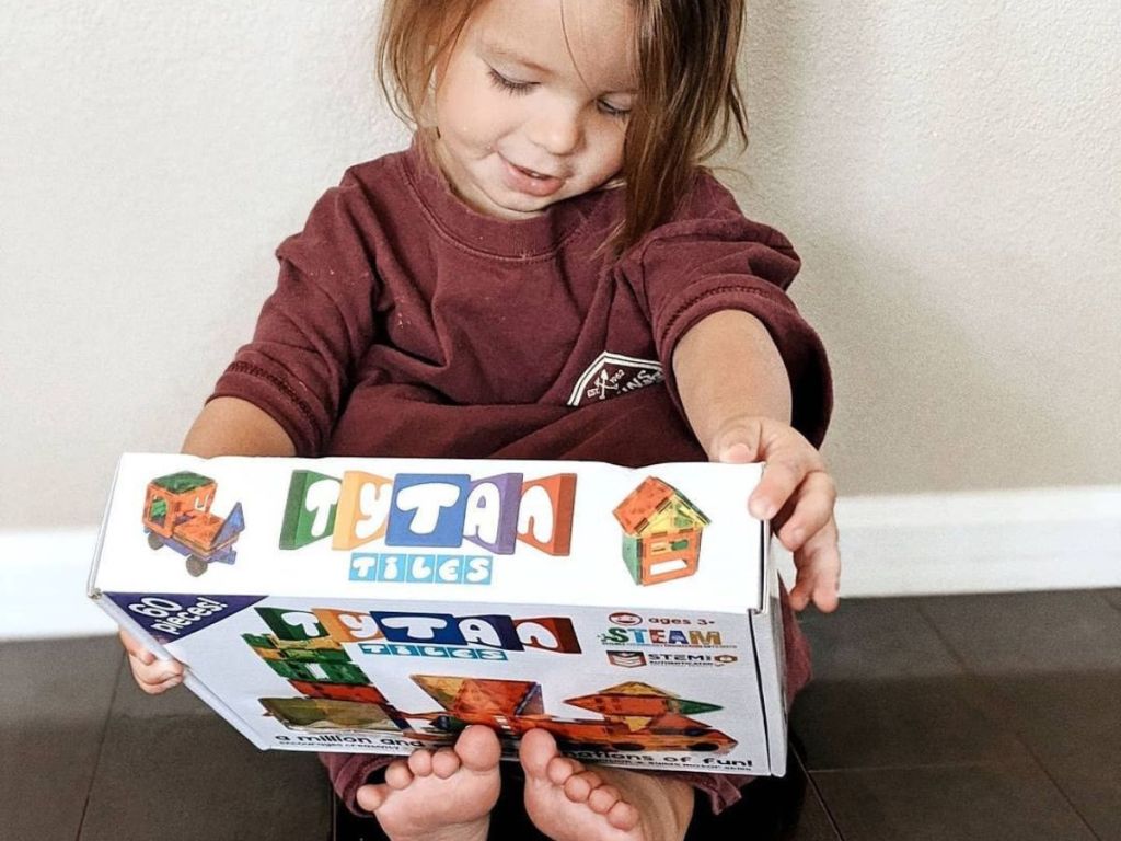 A little girl holding a box of Tytan tiles