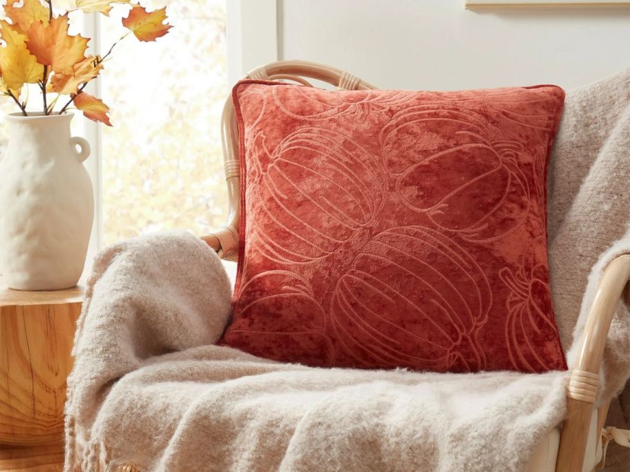 An orange decorative pillow on a chair 