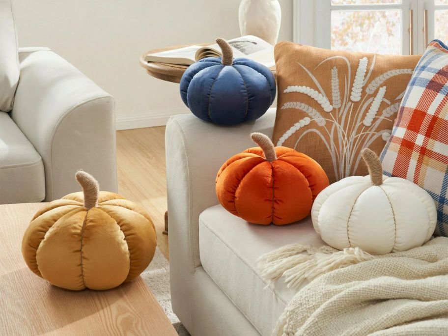A few velvet pumpkin decorative pillows on a chair 