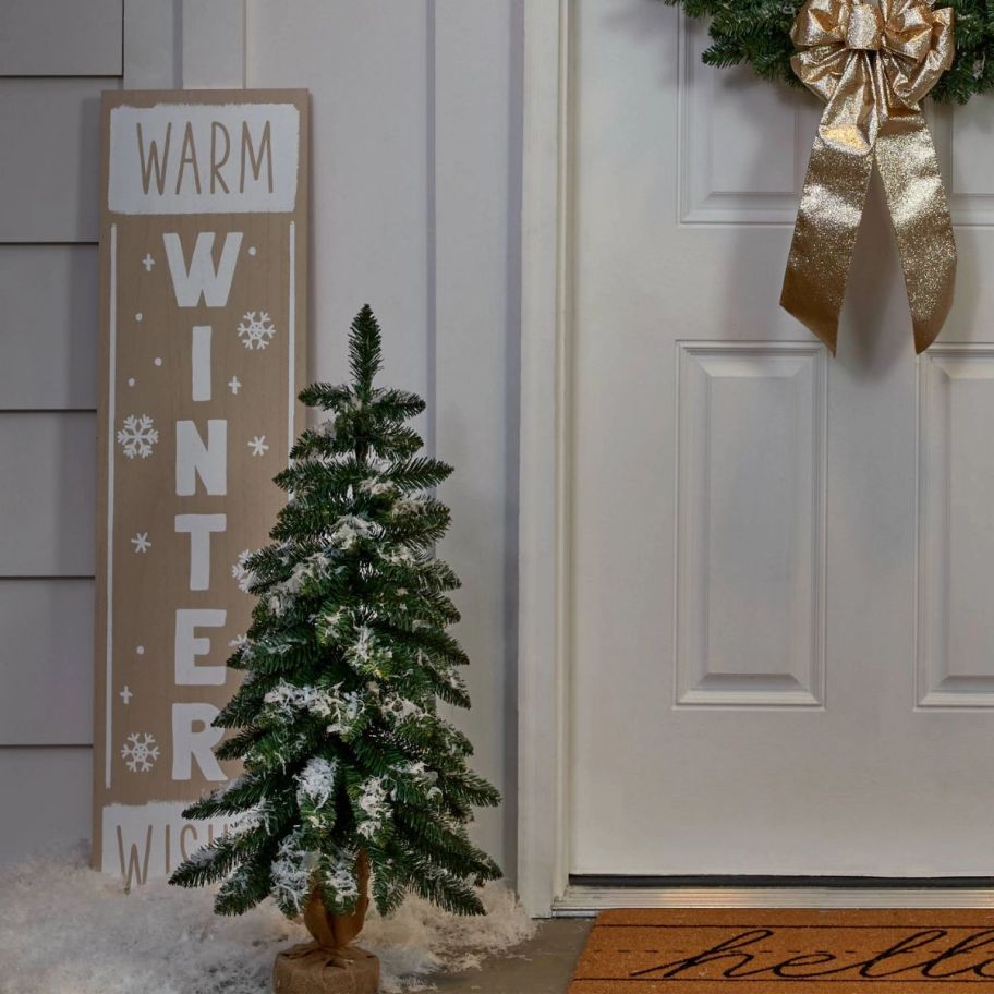 a burlap wrapped artificial Christmas tree by a front door