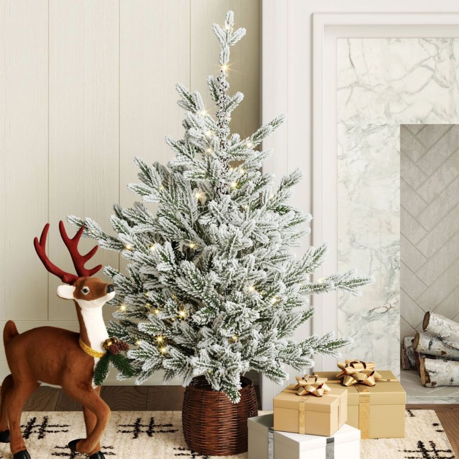 a small flocked potted artificial Christmas tree shown with wrapped gifts
