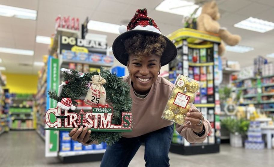 a smiling lady in a dollar general store holding christmas decor items