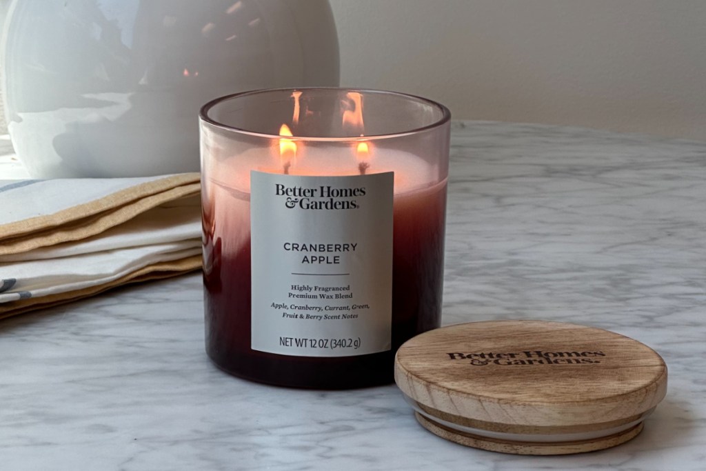 cranberry candle lit next to wood lid