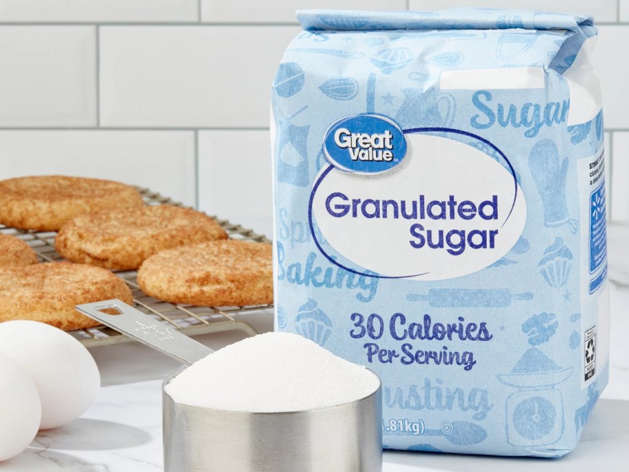 bag of sugar next to measuring cup full of sugar