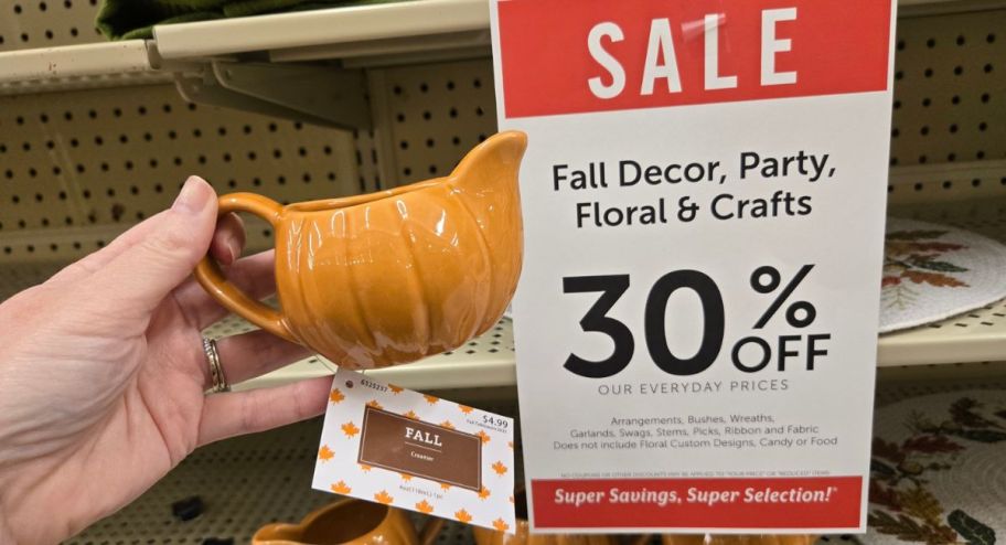 hand holding creamer with sign stating 30% off in the background