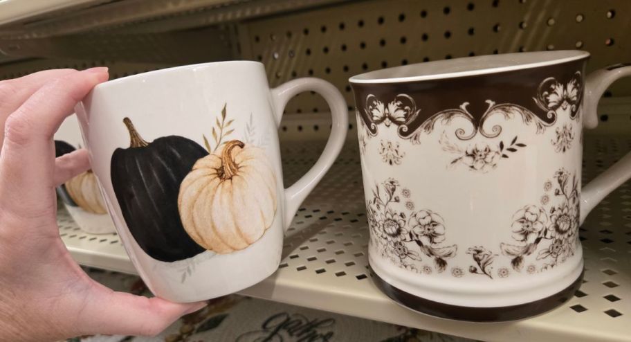 hand holding pumpkin and brown mugs