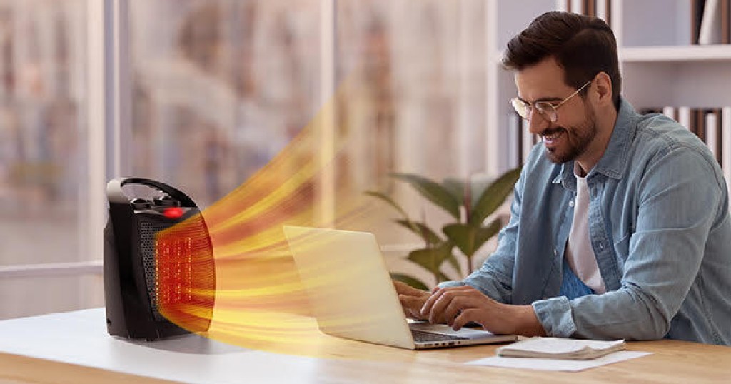 man sitting at a desk in front of a rintuf space heater