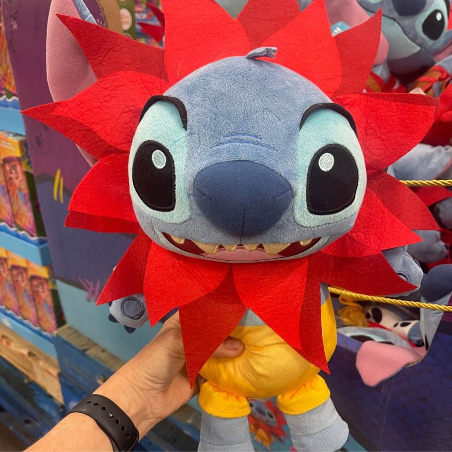 a womans hand holding a costumed stitch plush