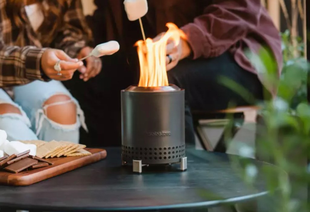 two people roasting smores with mini black firepit