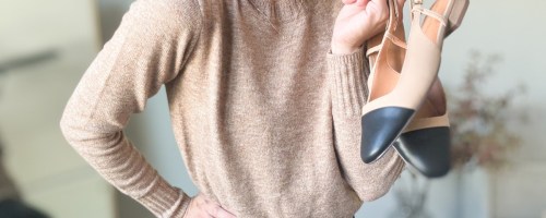 woman in tan sweater holding shoes