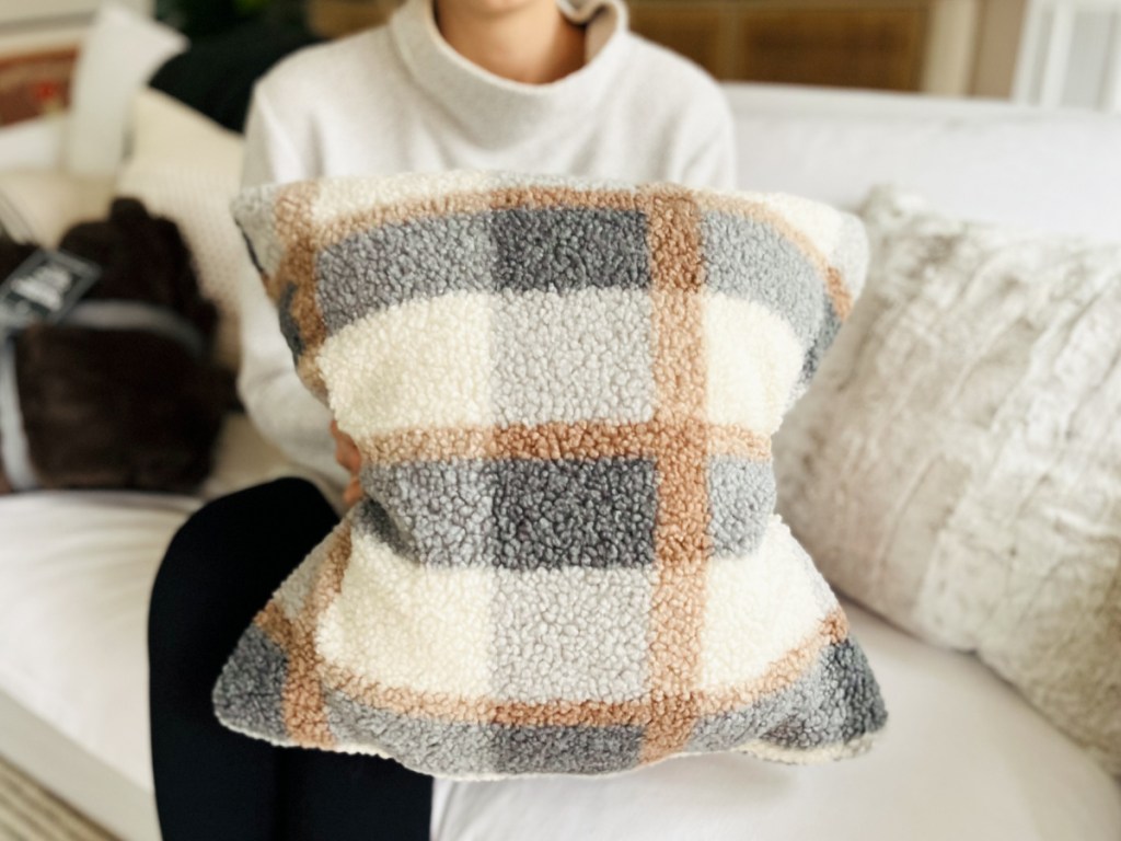 woman holding plaid cozy boucle pillow