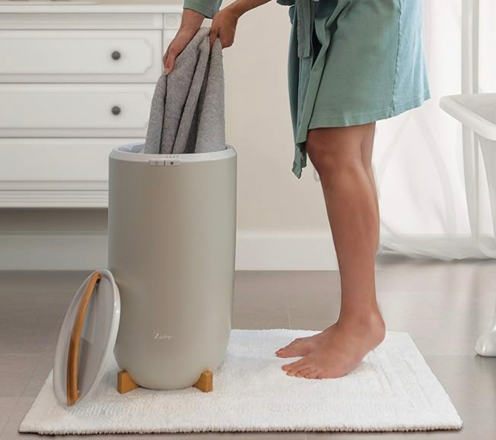 woman taking gray towel out of towel warmer in bathroom