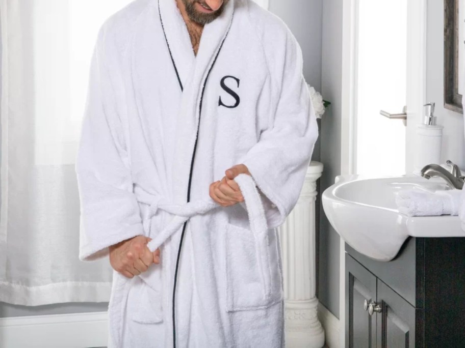 man wearing a white terry long sleeve bath robe with a monogrammed "S" on it