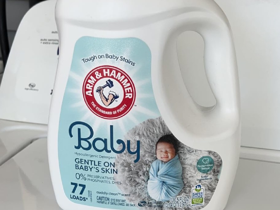 Bottle of arm & hammer baby detergent sitting on top of a washing machine