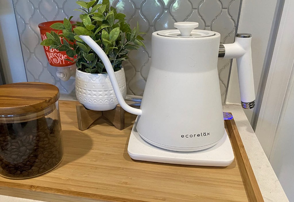 White electric tea kettle on wood cutting board in kitchen 