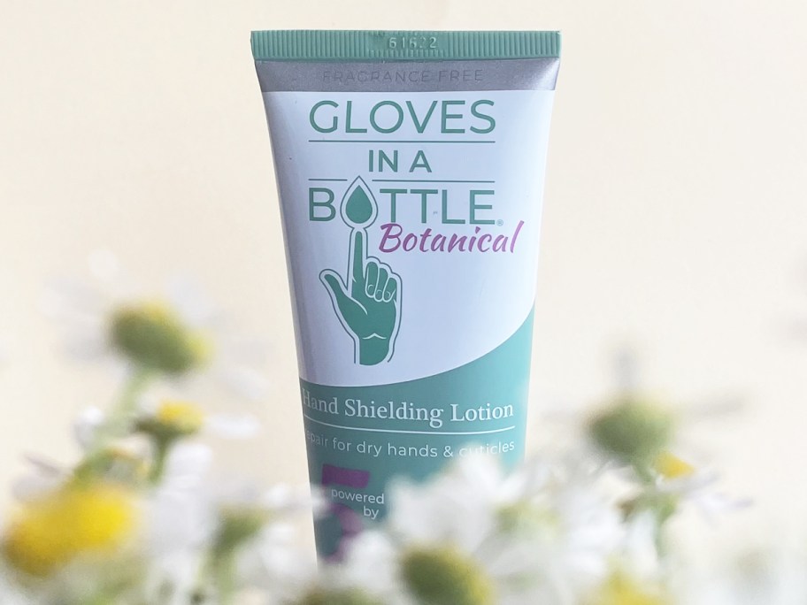 Gloves in a Bottle Botanical Hand Shielding Lotion with flowers below it