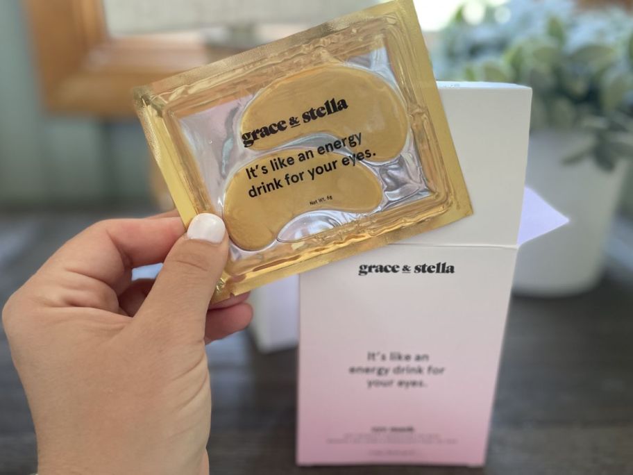 hand holding package of Grace & Stella gold under eye patches with the box behind it